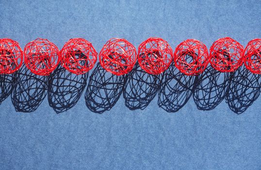 Set of red balls made from wire in a row against sun light