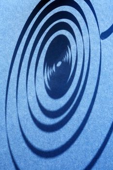 Industrial concept. Closeup of shadow of spiral on blue background