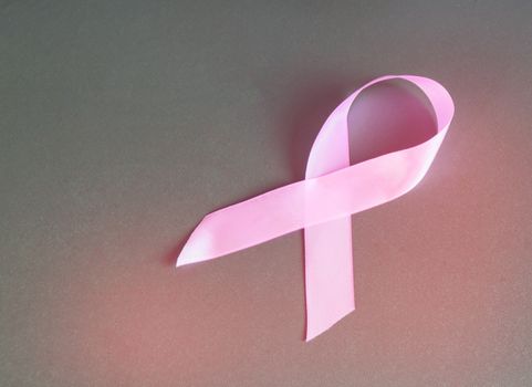 Pink ribbon to raise awareness of breast cancer, the image on a gray background, copy space.