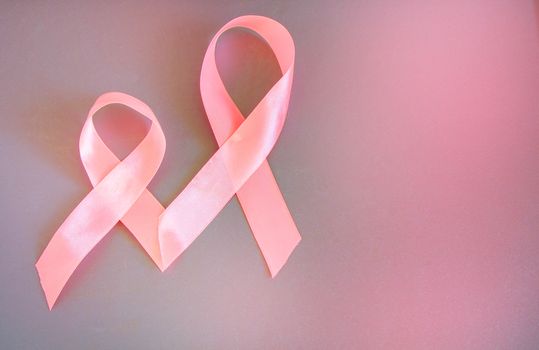 Two pink ribbons to raise awareness about breast cancer, the image on a gray background, copy space.