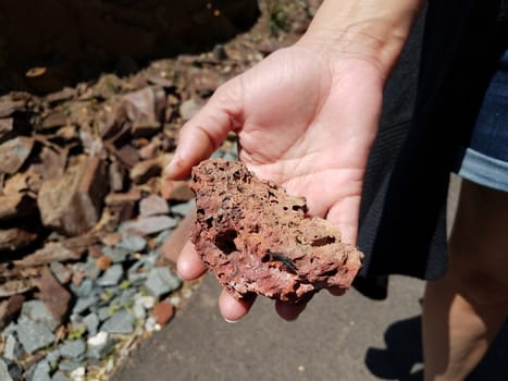 woman or female hand holding red rock or stone mineral
