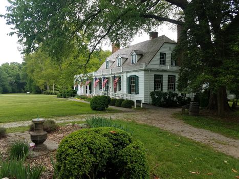 house with deck and flags of the United States and green bushes and lawn