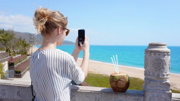 A beautiful young woman on a tropical beach with a phone in her hands. Rest, vacation, resort, beautiful life