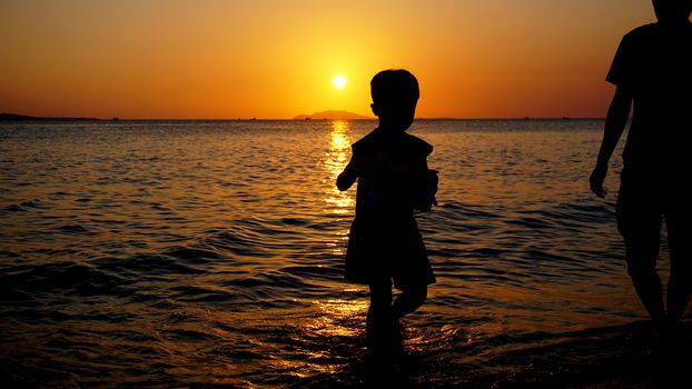 Father and child playing on the beach at the sunset time. Concept of friendly family.