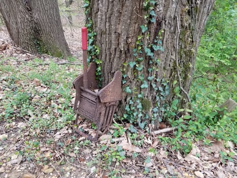 rusty metal mop wringer with red handle near tree with ivy