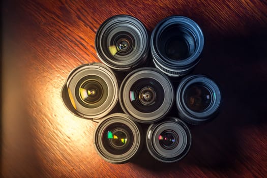 Set of various DSLR lenses with colorful reflections - shot from above on wooden background