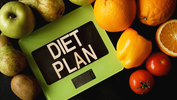 Concept diet. Healthy food, kitchen weight scale. Vegetables and fruits lettering Diet plan on black background