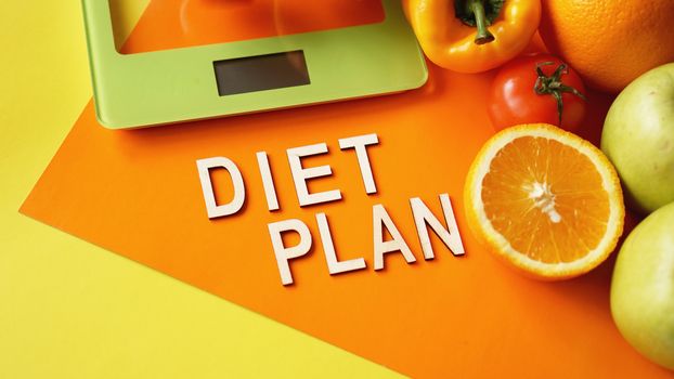 Concept diet. Healthy food, kitchen weight scale. Vegetables and fruits lettering Diet plan on orange background