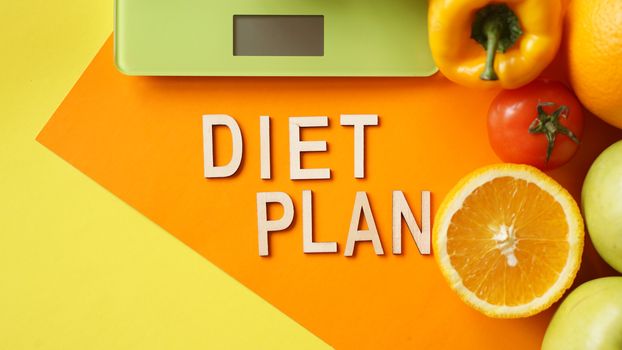 Concept diet. Healthy food, kitchen weight scale. Vegetables and fruits lettering Diet plan on orange background