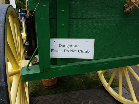 dangerous please do not climb sign on green stagecoach or wagon