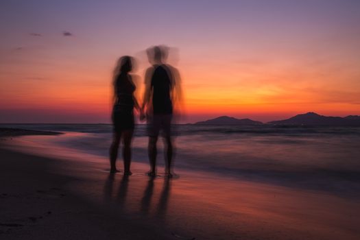 Blurry couple on the beach watching sunset in the summer