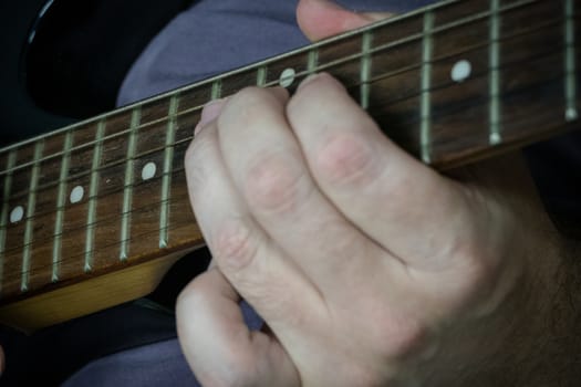 Close-up of man playing lead guitar solo on black guitar