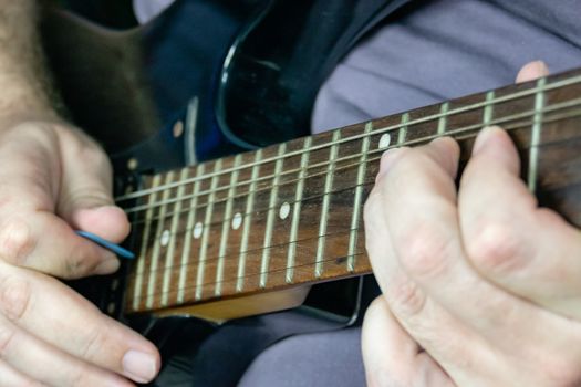 Close-up of man playing lead guitar solo on black guitar