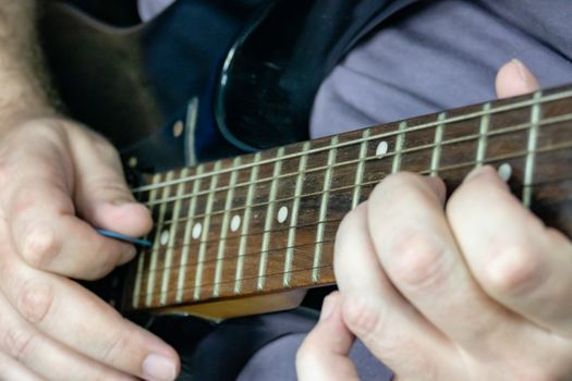 Close-up of man playing lead guitar solo on black guitar