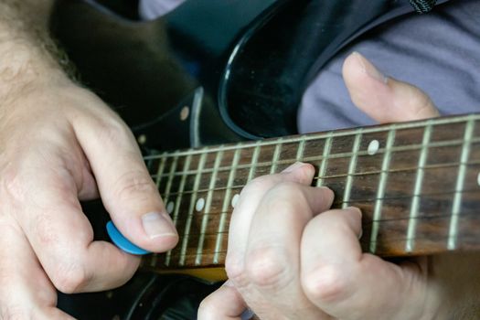 Close-up of man playing lead guitar solo on black guitar