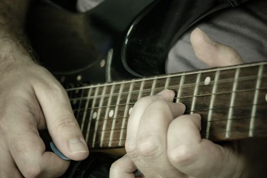 Close-up of man playing lead guitar solo on black guitar