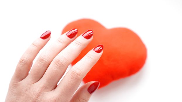 Female hand with red heart isolated on white background. Concept manicure.