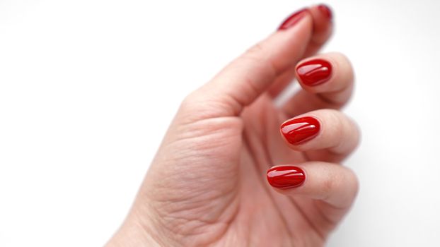 Beautiful female hand with fresh red manicure and nail isolated on white background