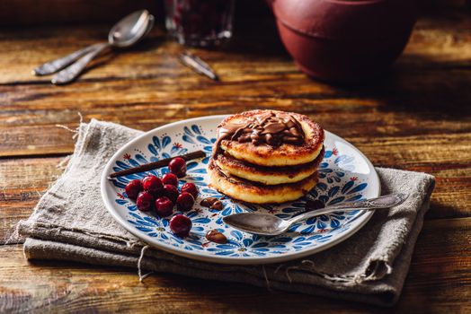 Quark Pancakes with Hazelnut Paste, Frozen Cherry and Vanilla Pod. Tea Pot with Spoons and Glass of Berries on Background.