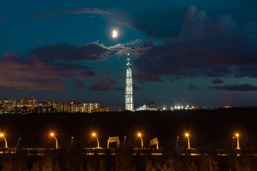 night cityscape. View of the Lakhta Center tower in St. Petersburg in the sunset with clouds and moon.