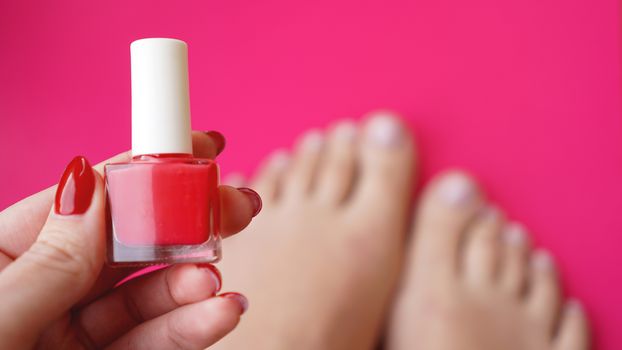 Young perfect groomed womans feet on pink background. Care about nails and clean, soft, smooth body skin. Pedicure and manicure beauty salon