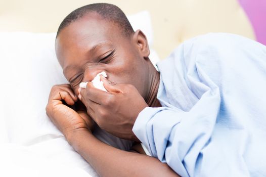 This young man lying on the bed is cold and feverish