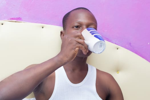 This young man lying in bed drinking coffee