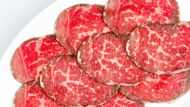 Top view of some raw beef on a plate over white background