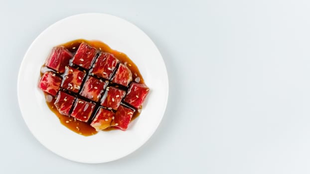 Top view of some raw beef with sauce on a plate over white background