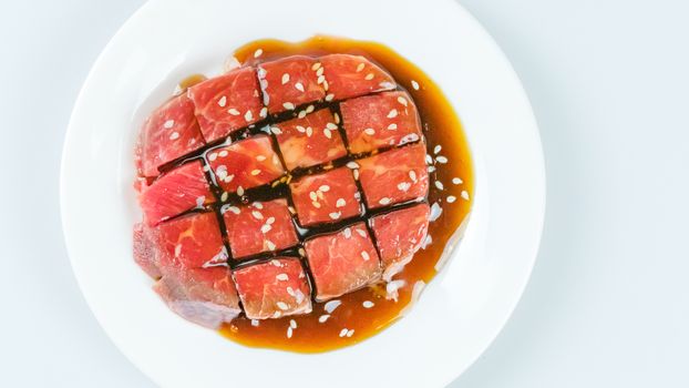 Top view of some raw beef with sauce on a plate over white background