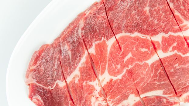 Top view of some raw beef on a plate over white background