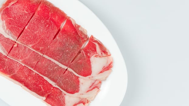 Top view of some raw beef on a plate over white background