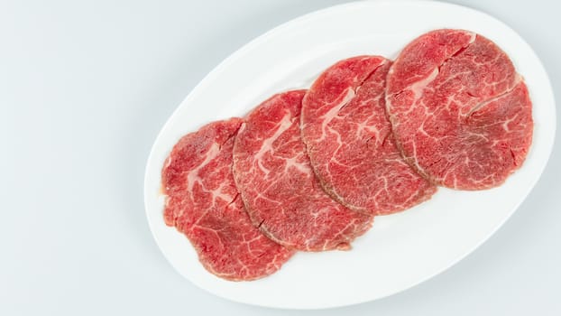 Top view of some raw beef on a plate over white background