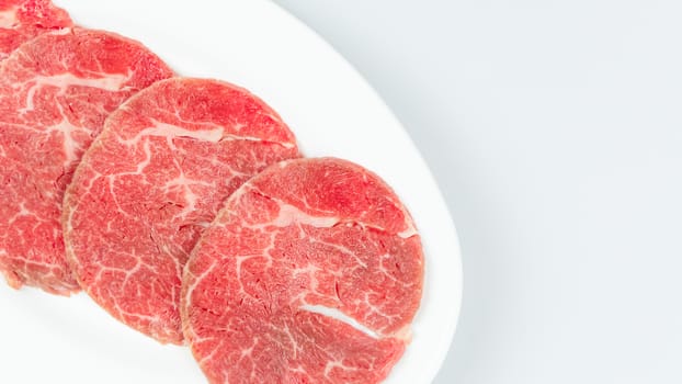 Top view of some raw beef on a plate over white background