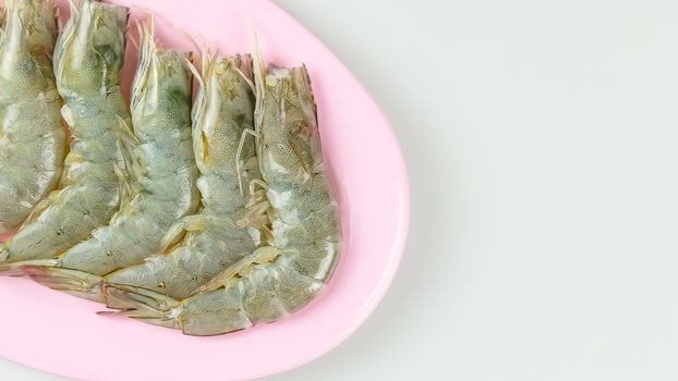 top view raw prawn on pink dish over white background