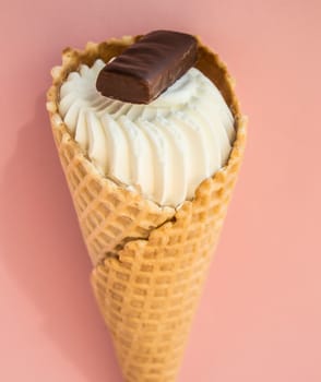 Vanilla ice cream in a waffle cone with chocolate on a pink background, copy space, vertical shot.