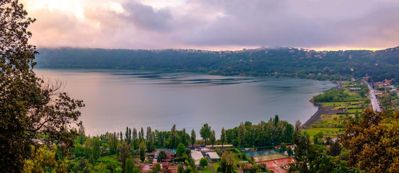 panoramic view of Albano Lake or Lago di Abano in the Roman Castle or Castelli Romani area near Rome in Lazio at sunset with purple sky .