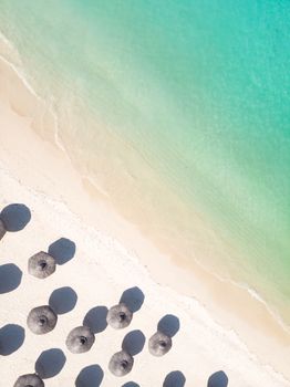 Aerial view of amazing tropical white sandy beach with palm leaves umbrellas and turquoise sea, Mauritius.