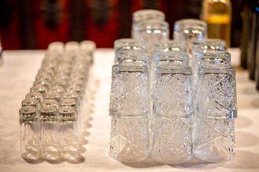 Empty glasses on the white table in restaurant. Lot of crystal glasses arranged on the table for wedding reception.