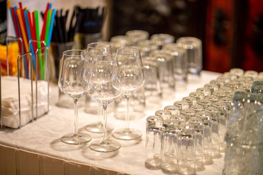 Empty glasses on the white table in restaurant. Lot of crystal glasses arranged on the table for wedding reception.