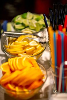 Orange, lemon and lime slices arranged on the glass bowl setting on holiday table. Focus on lemon slices.