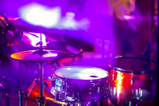 Empty abstract light illuminated stage with drumkit and microphone. Drums in multicolored light during celebrations on stage.