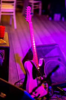 Electric guitar and sound amplifier in multicolored light during celebrations on stage. Empty abstract light illuminated stage with electric guitar and sound amplifier