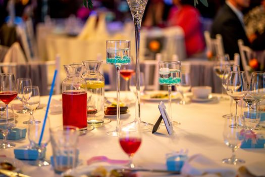 Jugs with lemonade and glasses on table at wedding party or banquet. Glasses and jugs with drinks setting on the festive table in restaurant.