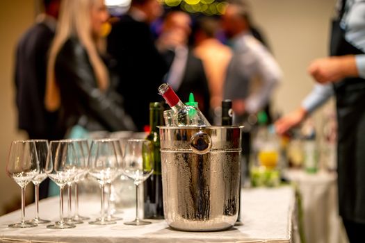 Bucket with ice, wine bottles and empty glasses on table in restaurant. Ice bucket, wine glasses and bottles arranged on the table for wedding reception.