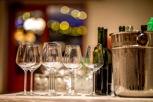 Empty glasses, wine bottles and bucket with ice on table in restaurant. Ice bucket, wine glasses and bottles arranged on the table for wedding reception.