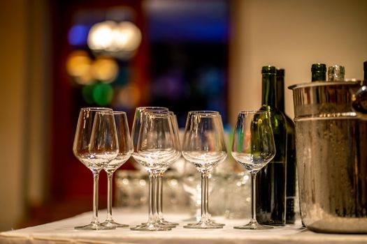 Empty glasses, wine bottles and bucket with ice on table in restaurant. Ice bucket, wine glasses and bottles arranged on the table for wedding reception.