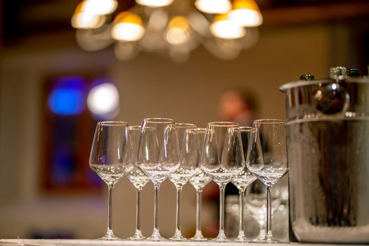 Empty glasses, wine bottles and bucket with ice on table in restaurant. Ice bucket, wine glasses and bottles arranged on the table for wedding reception.