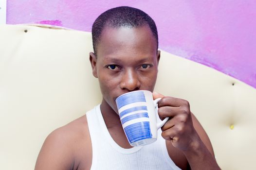 this young cheerful man drinks coffee in bed