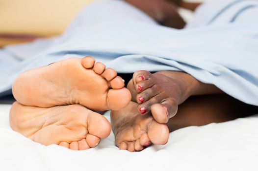 This couple lying in bed and showing their bare feet entwined